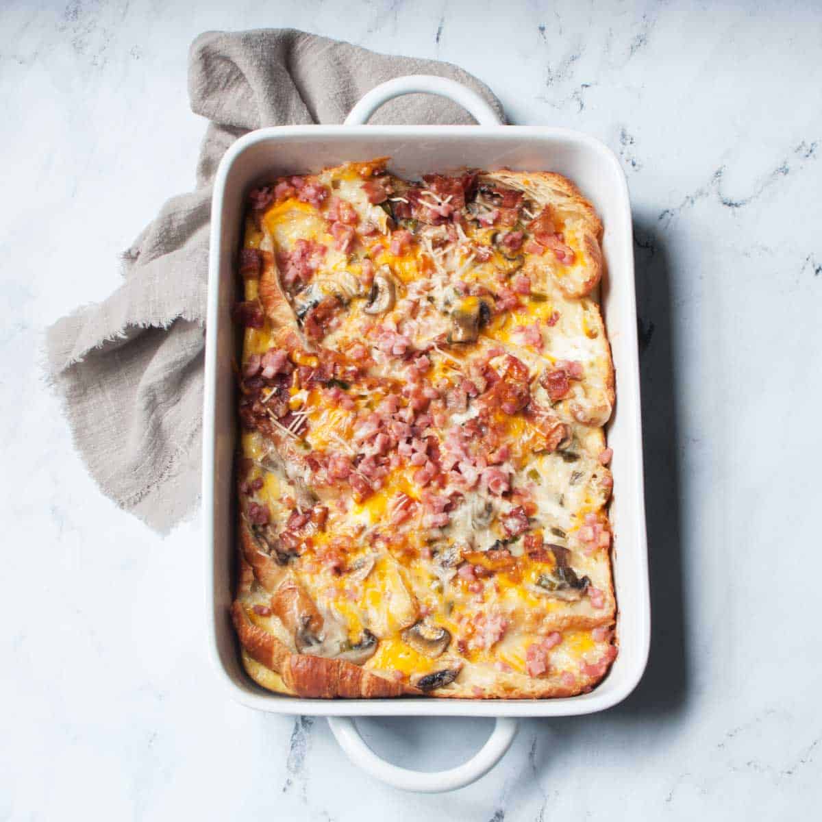 Overnight croissant breakfast casserole in a white baking dish.