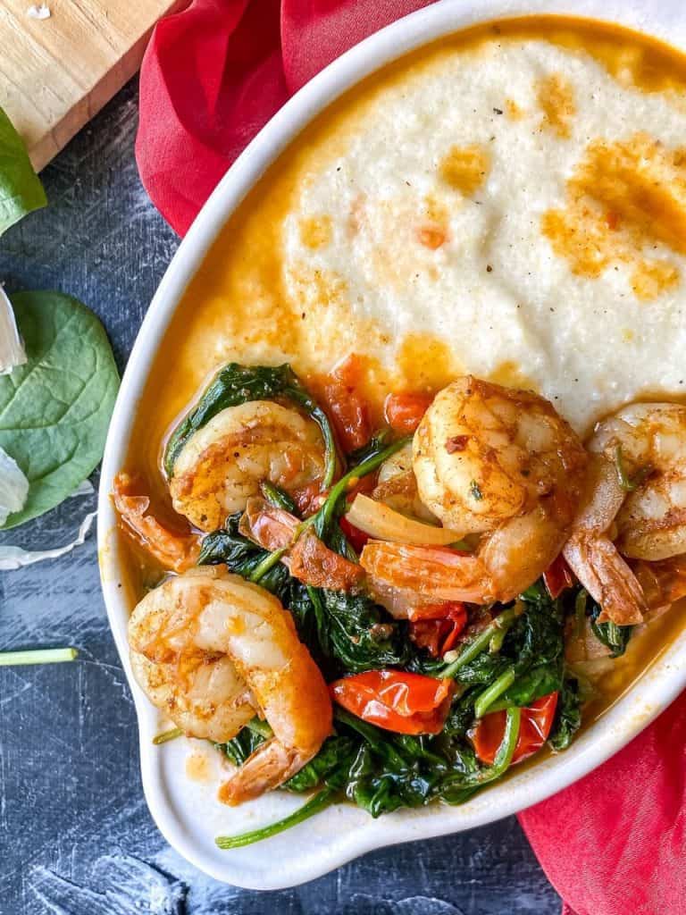 Shrimp and grits in a white serving bowl.