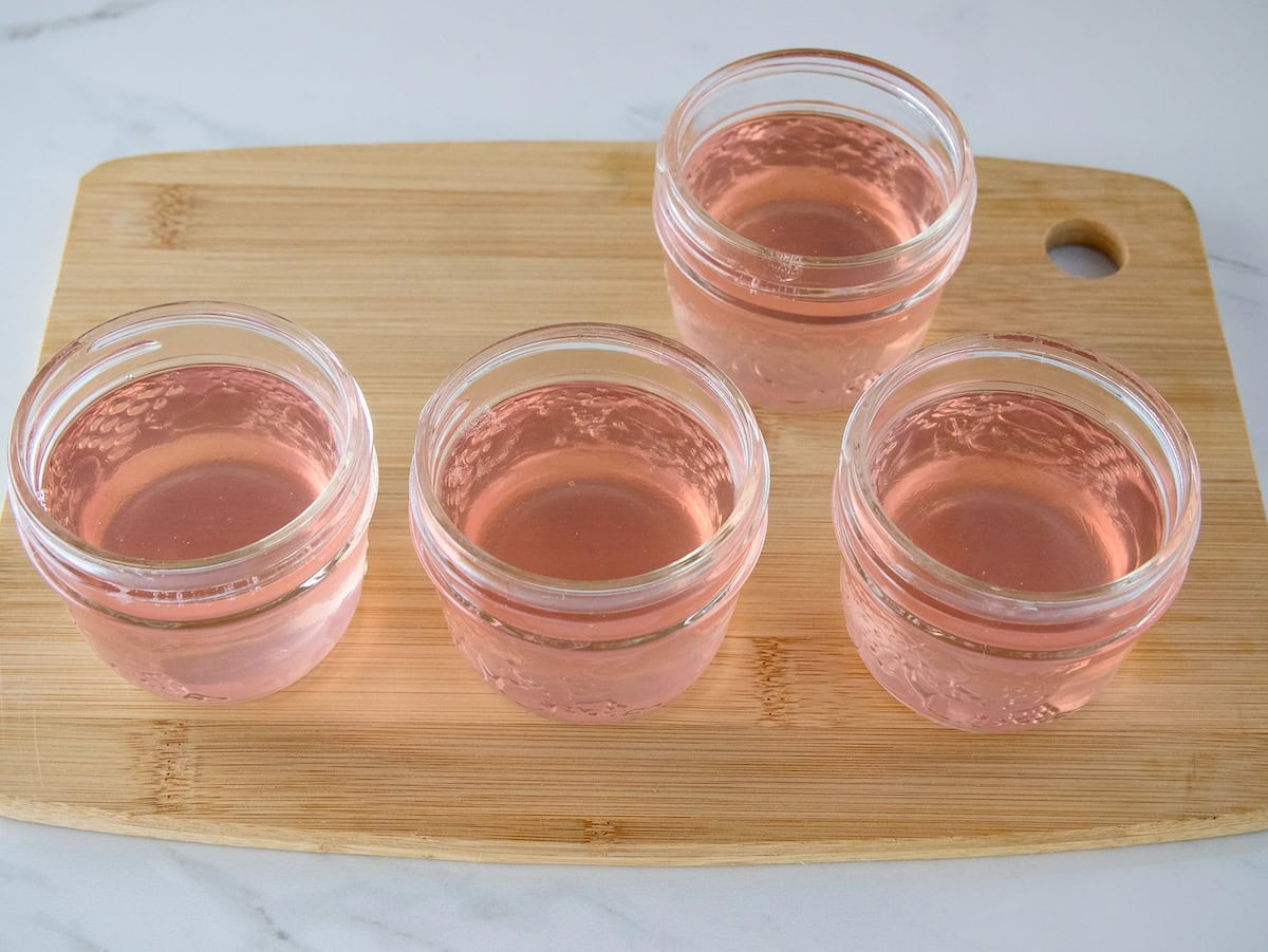 Jelly jars filled with homemade red clover jelly.