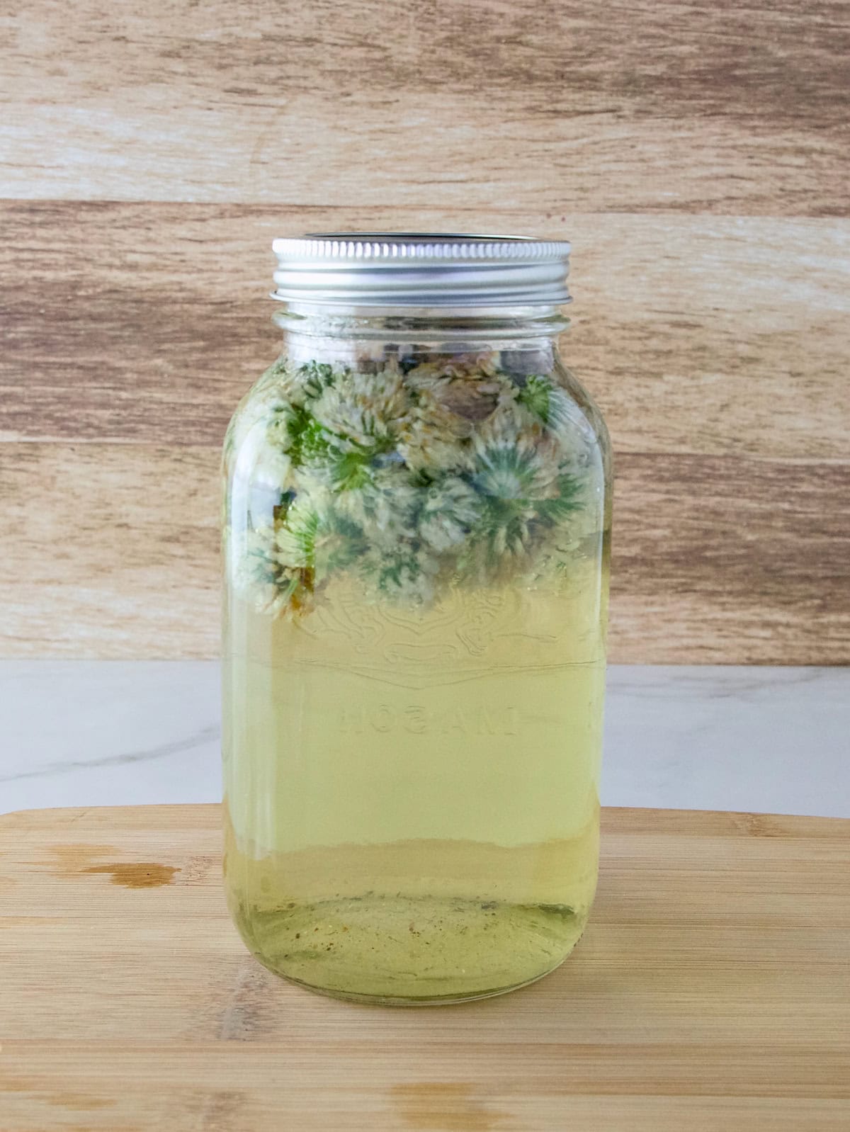 Red clover flower tea steeping in a mason jar.