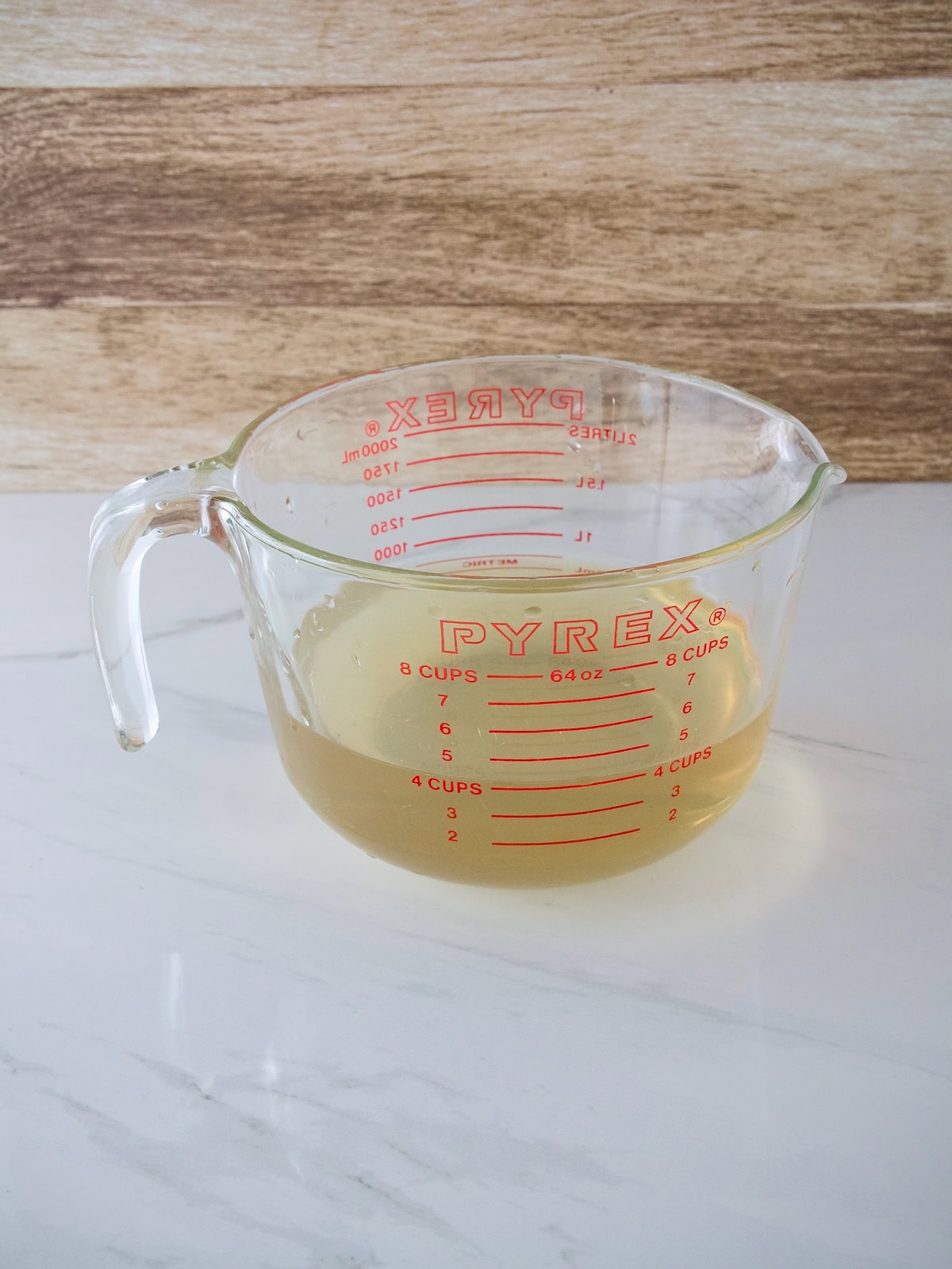 A large measuring cup filled with 4 cups of red clover tea.