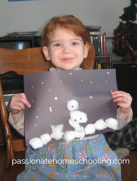 Young girl holding her cotton ball snowman craft.