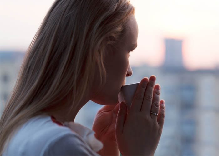 Woman outside drinking coffee.