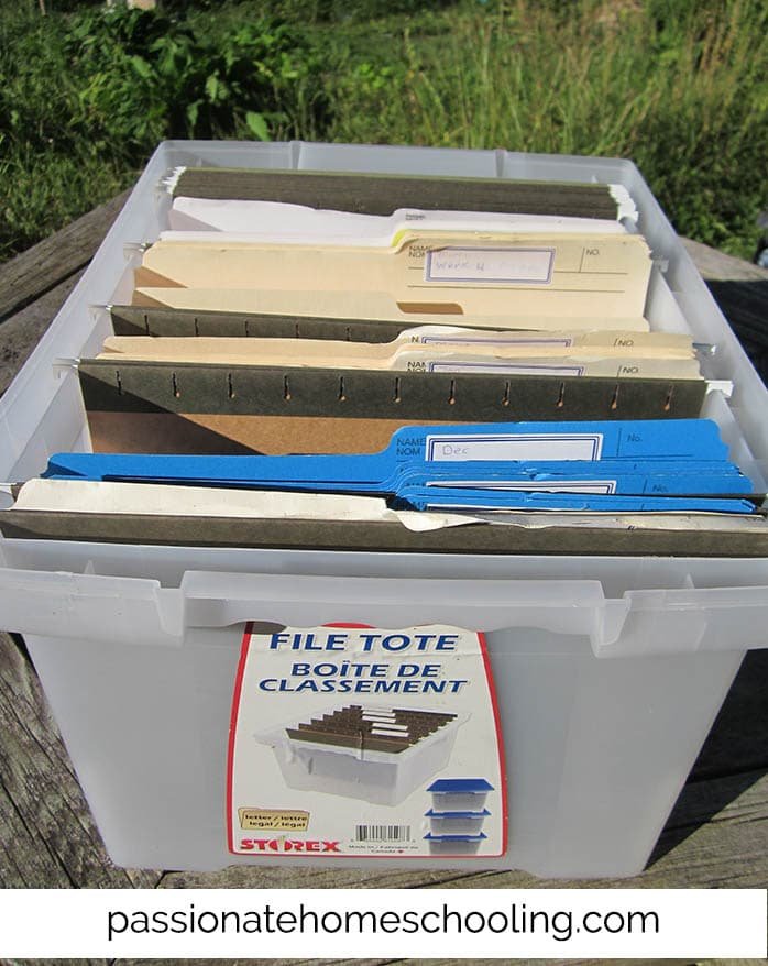Plastic tote bin filled with file folders to organize homeschool lessons.
