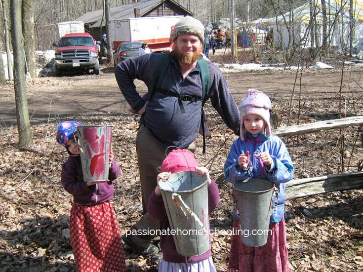 Our kids with their dad holding up the maple syrup buckets they decorated.