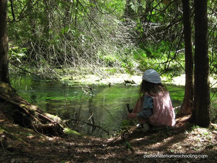 Girl sitting by a small river.