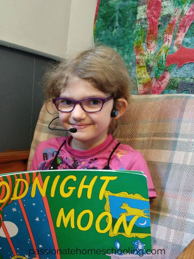 Young girl reading a book and wearing a Forbrain headset.
