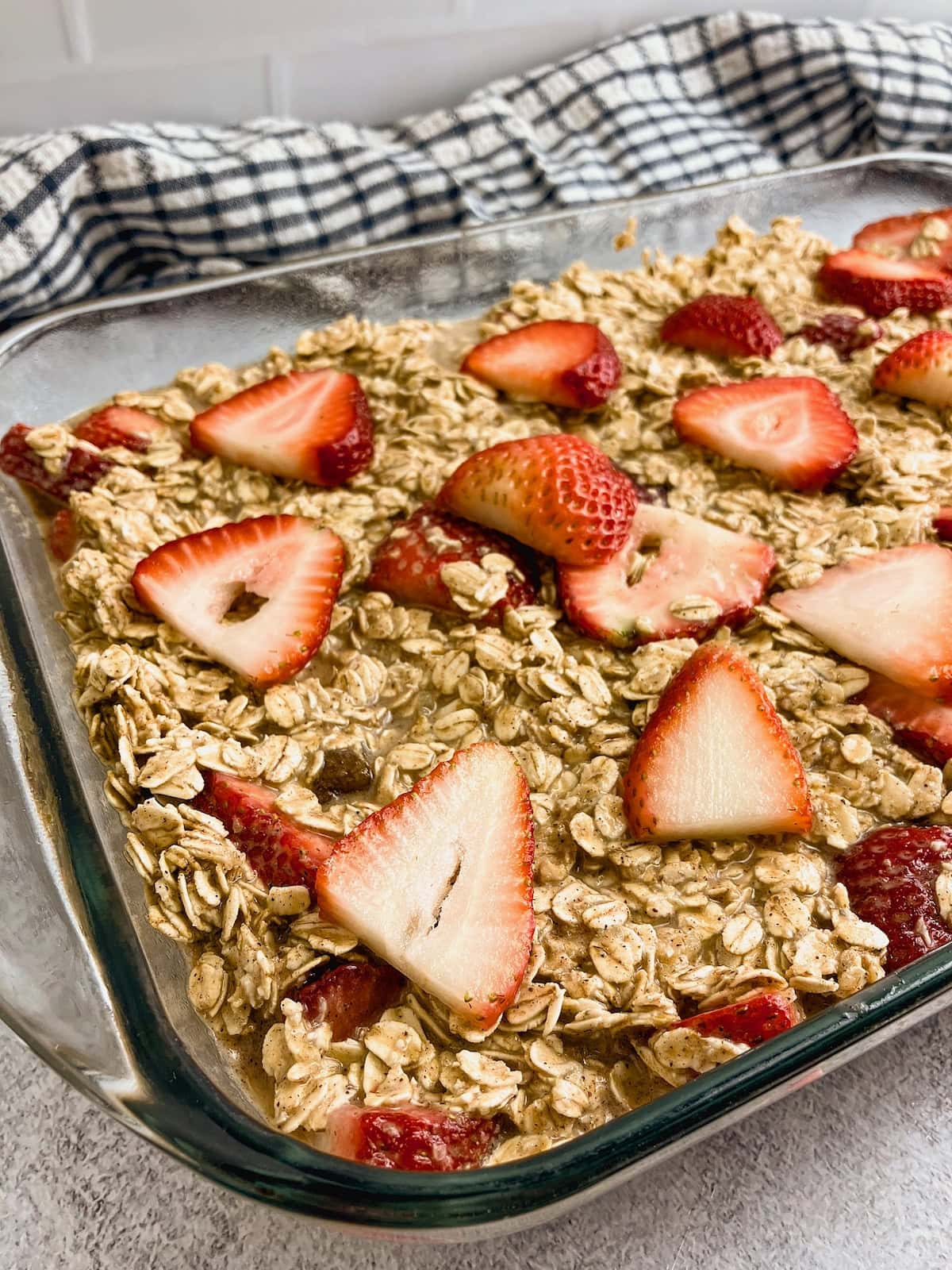 Strawberry baked oatmeal batter in a 9x13 baking dish with fresh sliced strawberries spread over the top.
