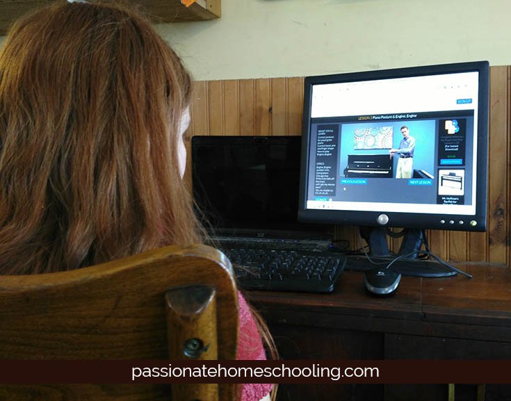 Girl watching video piano lessons on a computer.