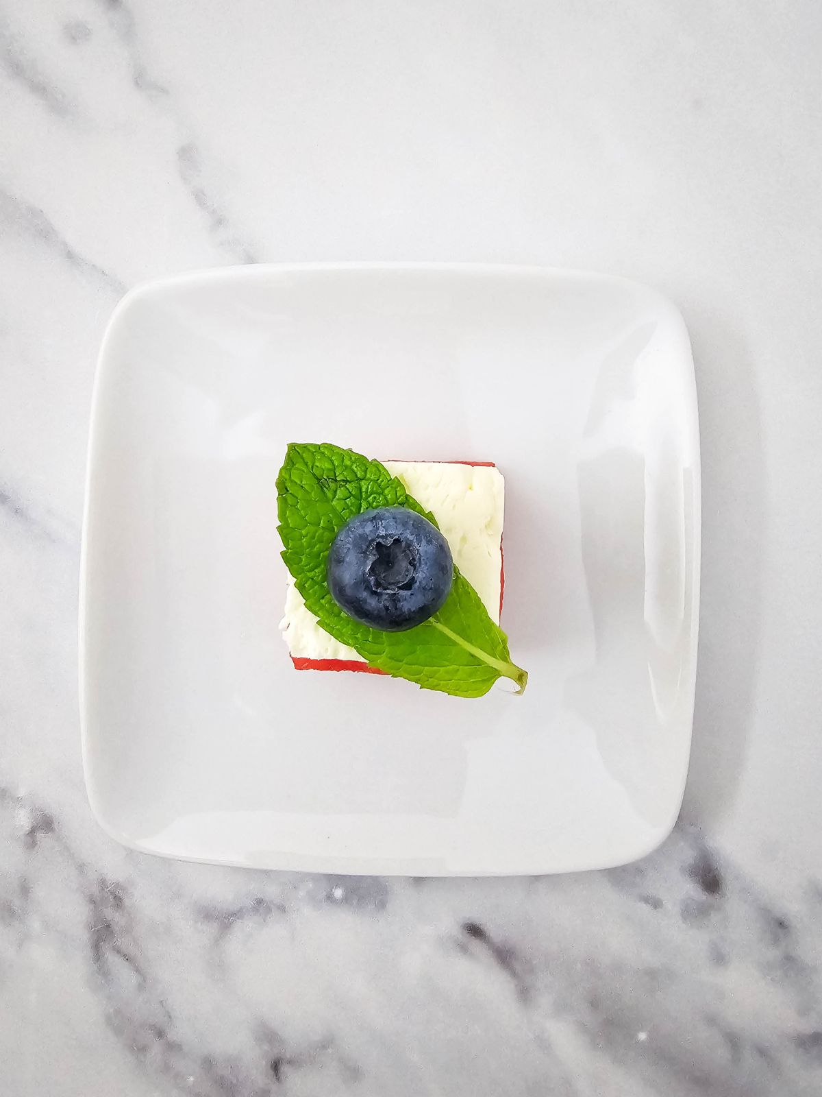A blueberry was placed on top of the mint leaf.