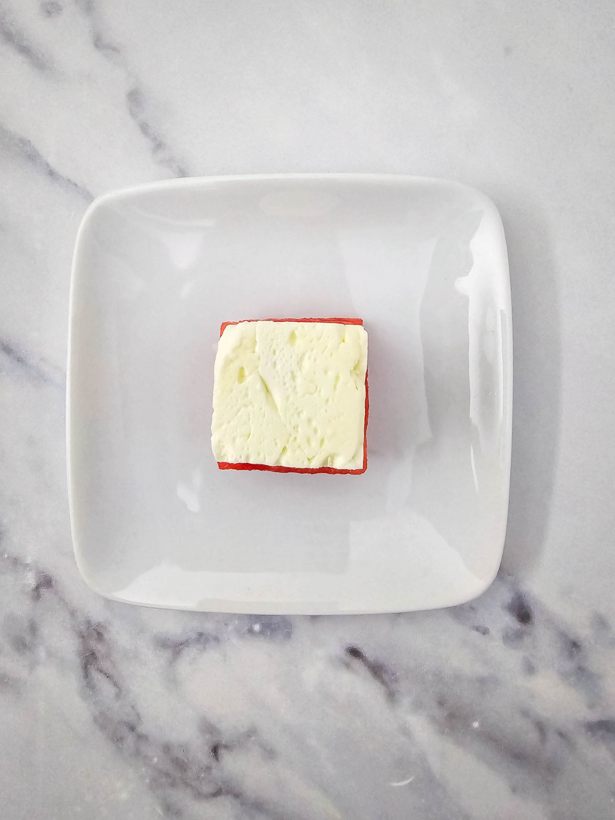 A cube of feta cheese on top of the watermelon.