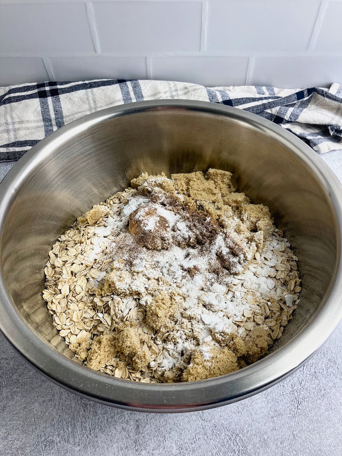 A large mixing bowl with rolled oats, brown sugar, salt, ground cinnamon, and baking powder.