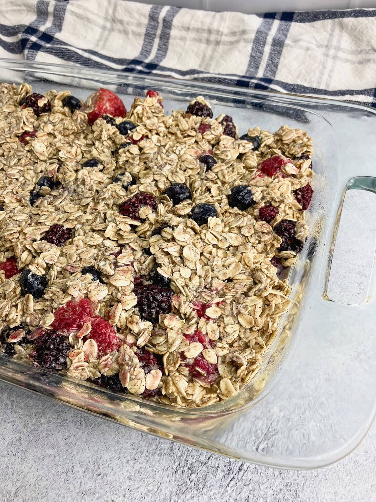 A glass baking dish filled with berry baked oatmeal batter.