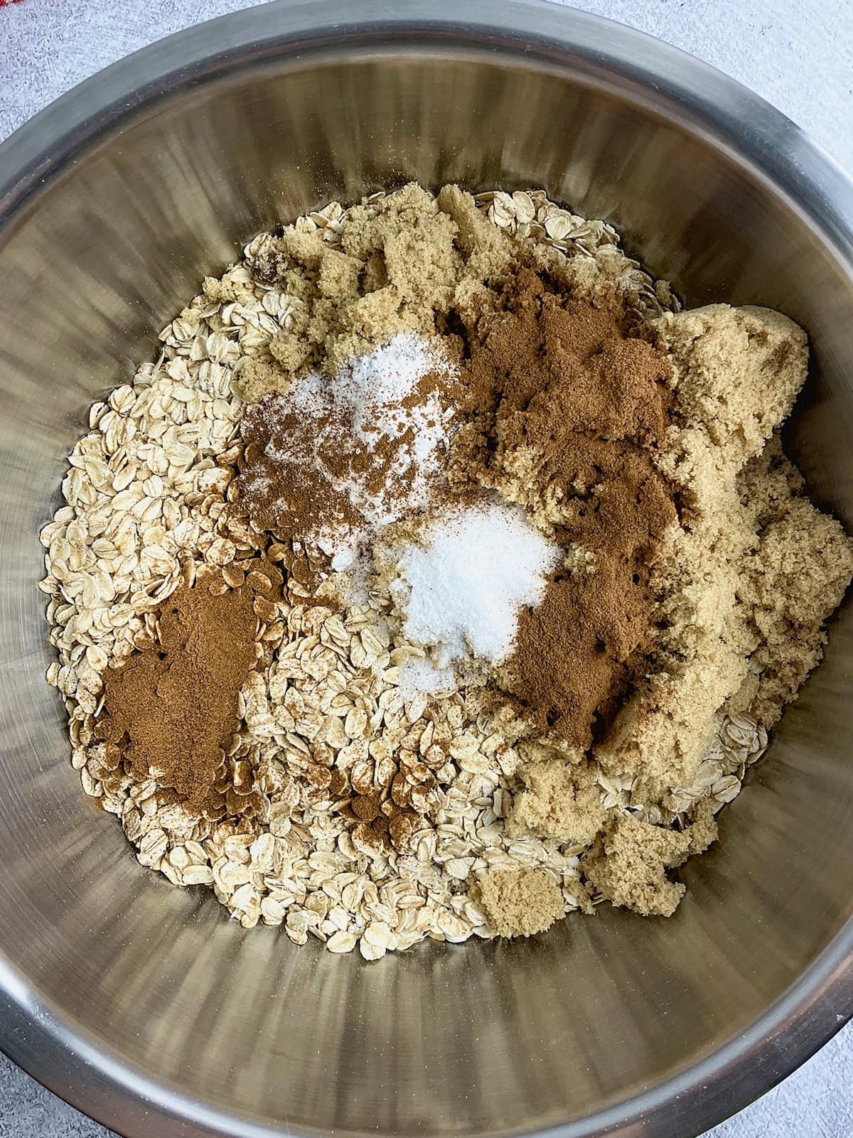 A mixing bowl with oats, brown sugar, baking powder, cinnamon, and salt.