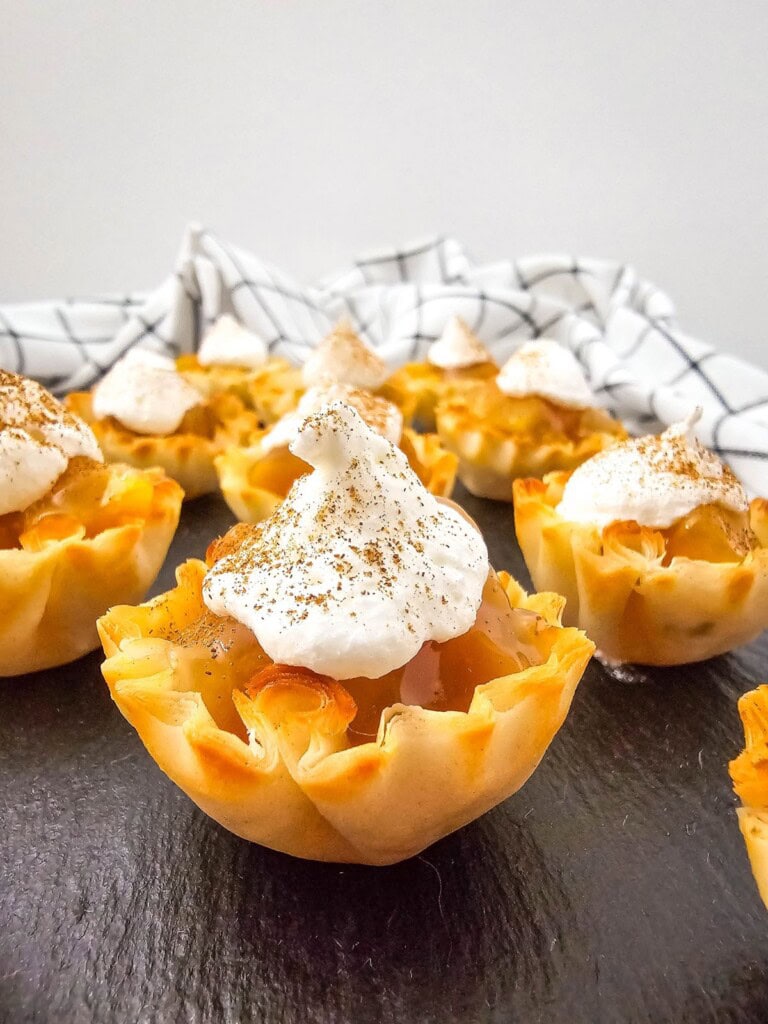 Peaches and cream pie bites are topped with whipped topping and cinnamon.