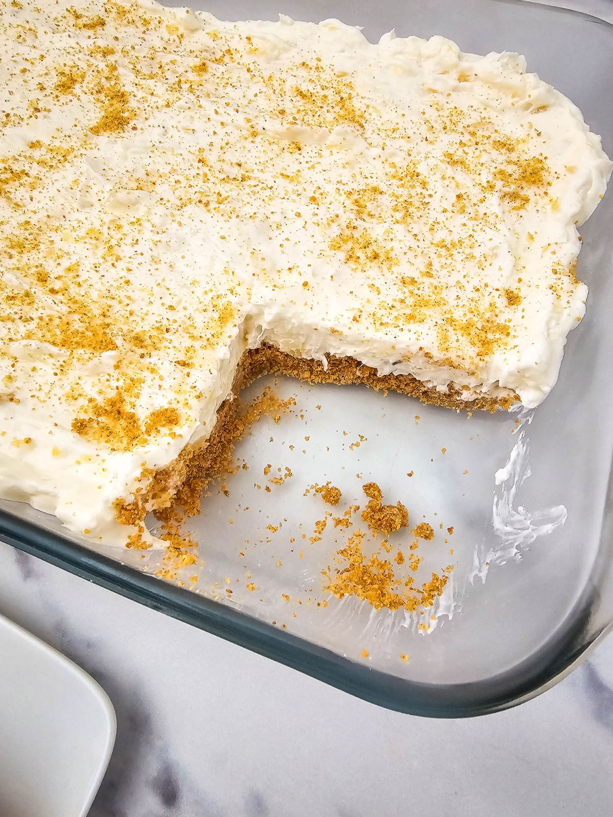 A dish of pineapple dream dessert with a slice removed.