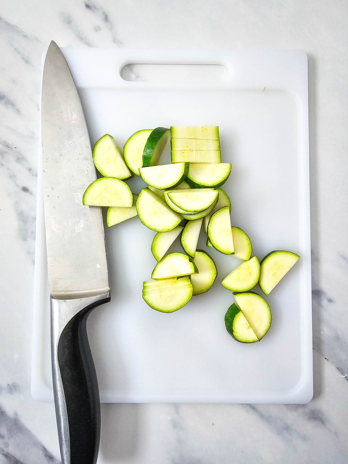 Zucchini sliced and halved on a cutting board.
