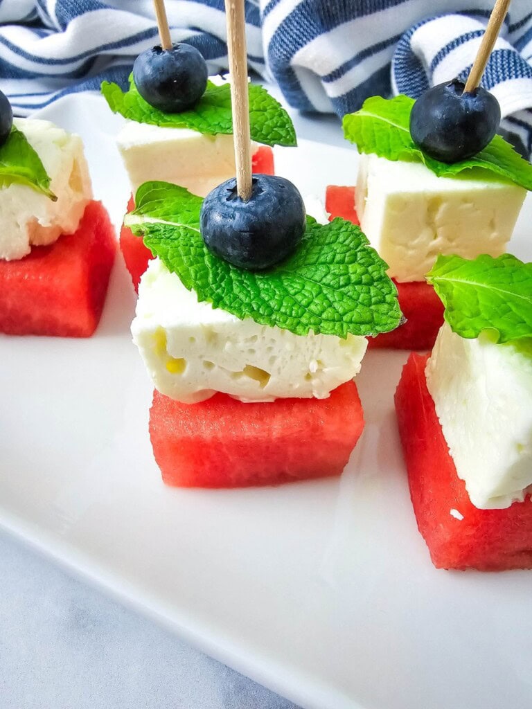 Watermelon, feta cheese, and blueberry skewers on a platter.