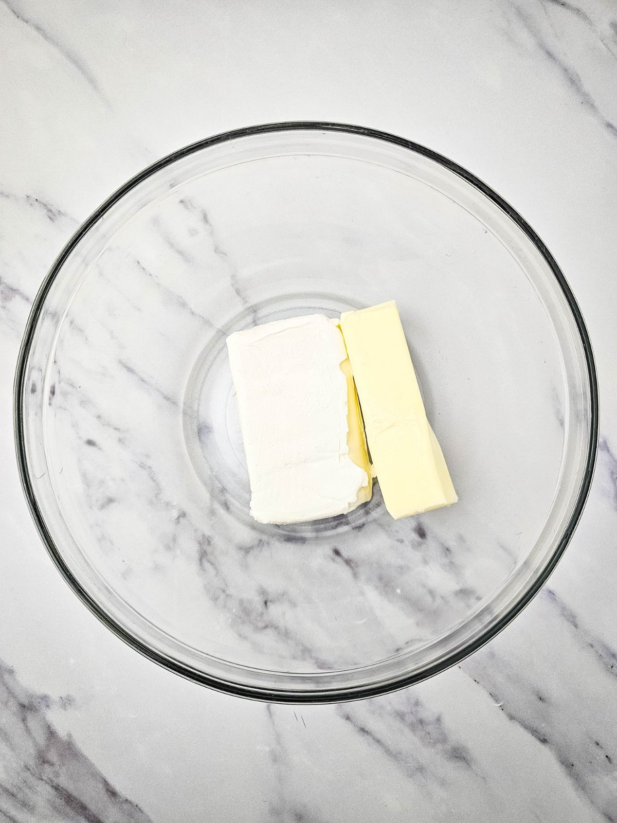 A mixing bowl with softened butter and cream cheese.