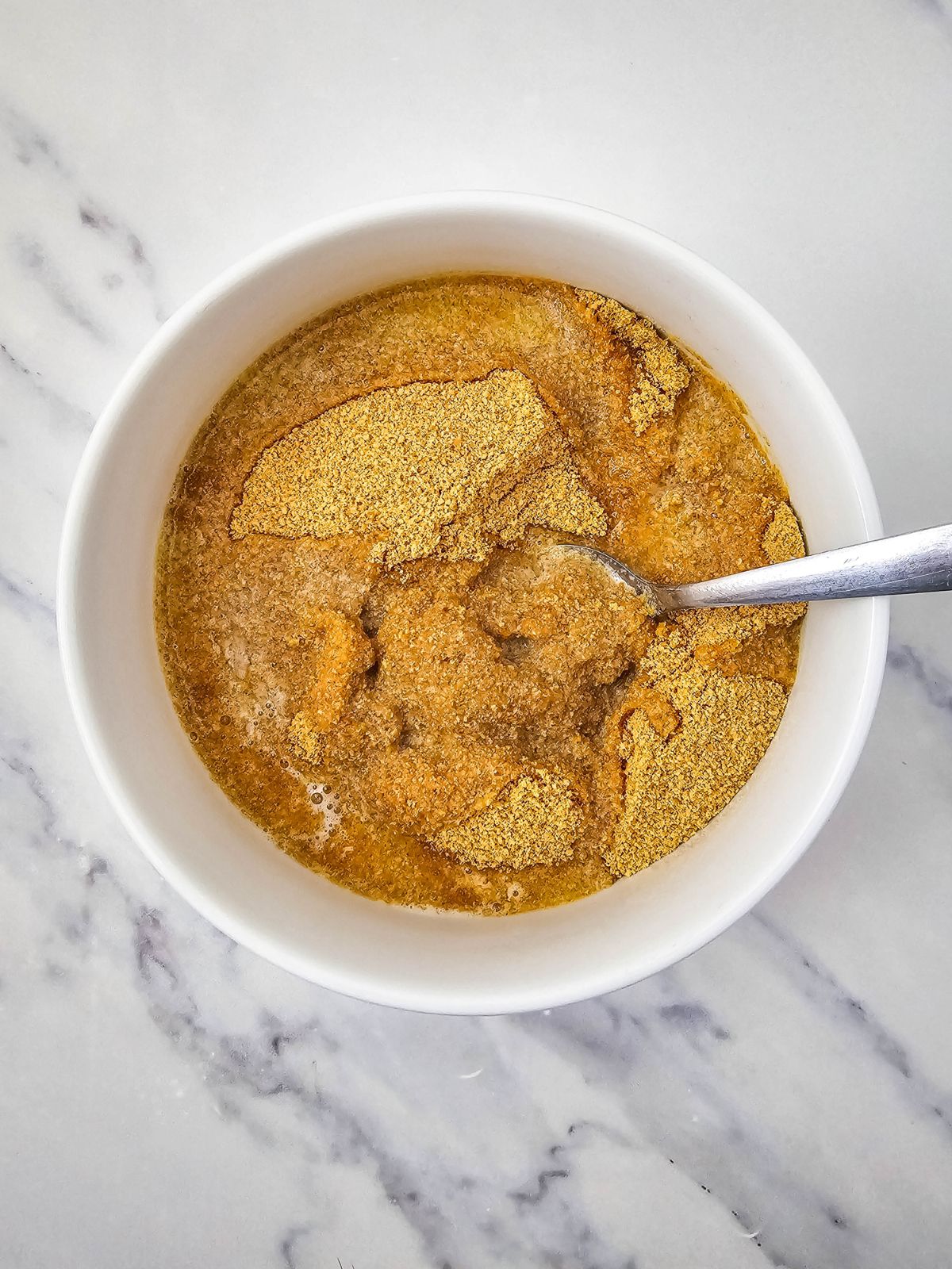 A bowl of graham cracker crumbs and melted butter poured over them.
