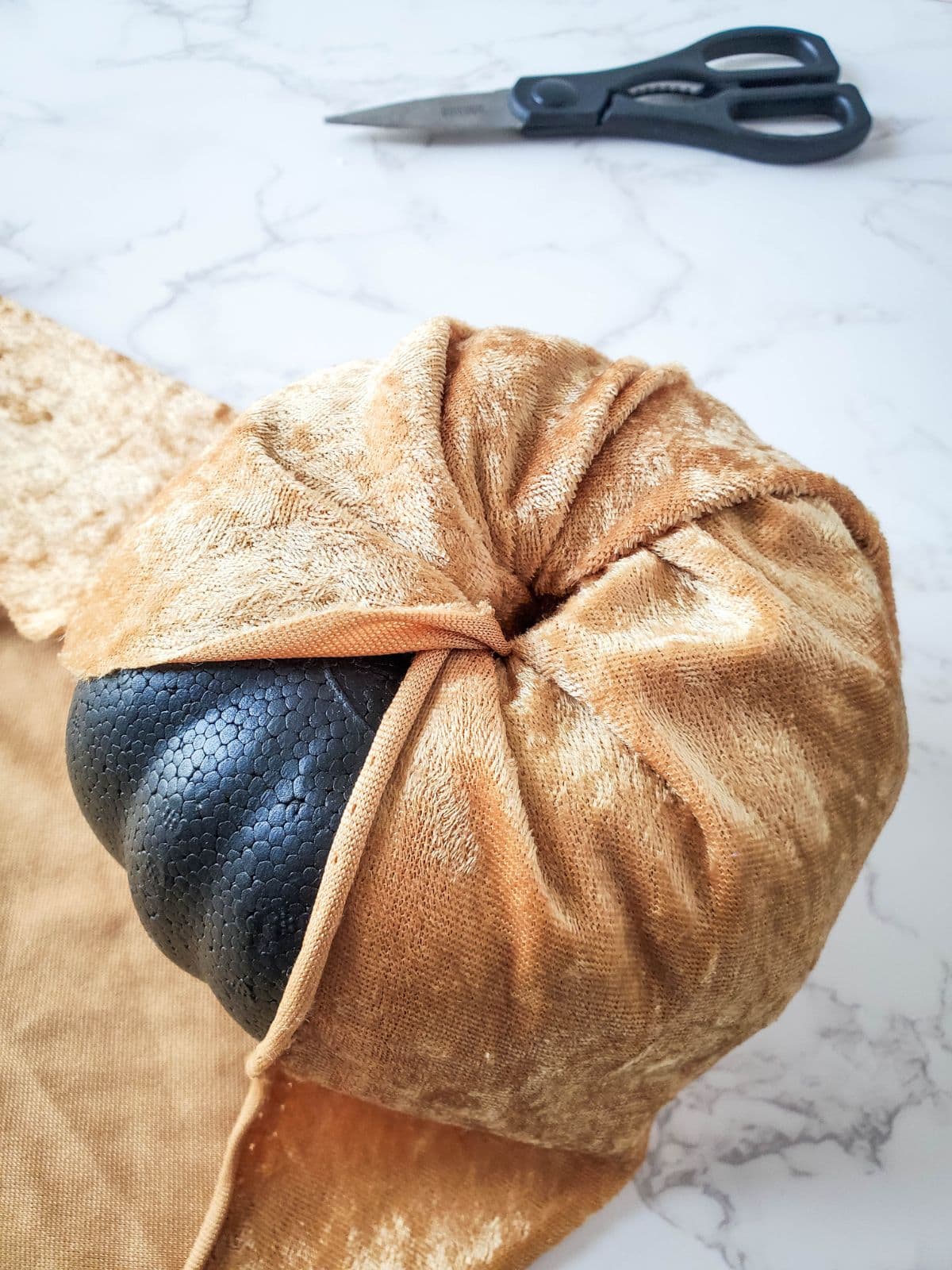 Wrapping the fabric around the pumpkin and stuffing it into the hole.