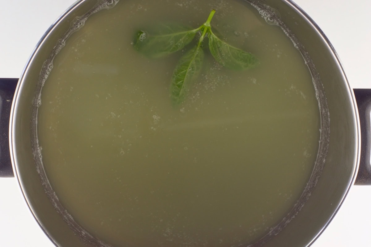 A pot with cucumber juice and basil leaves.