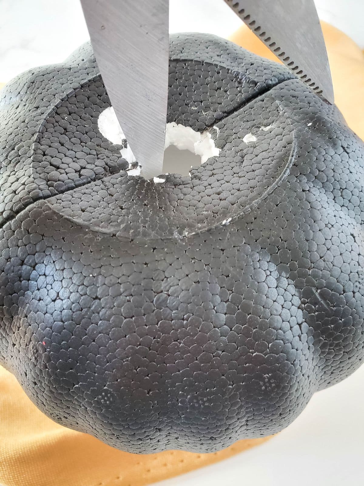 Cutting a hole in the foam pumpkin.