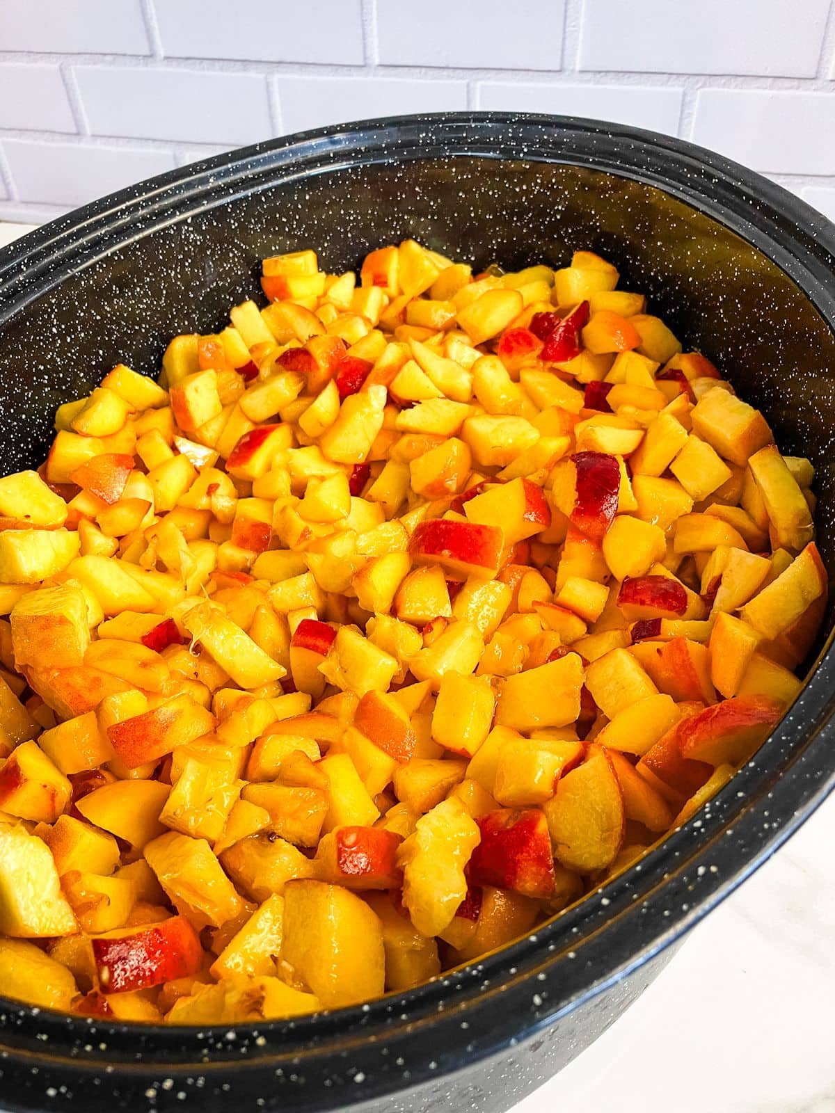 A roasting pan filled with diced peaches.
