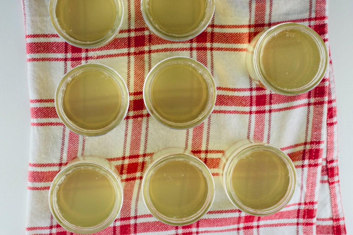Eight mason jars filled with cucumber basil jelly are sitting on a towel.