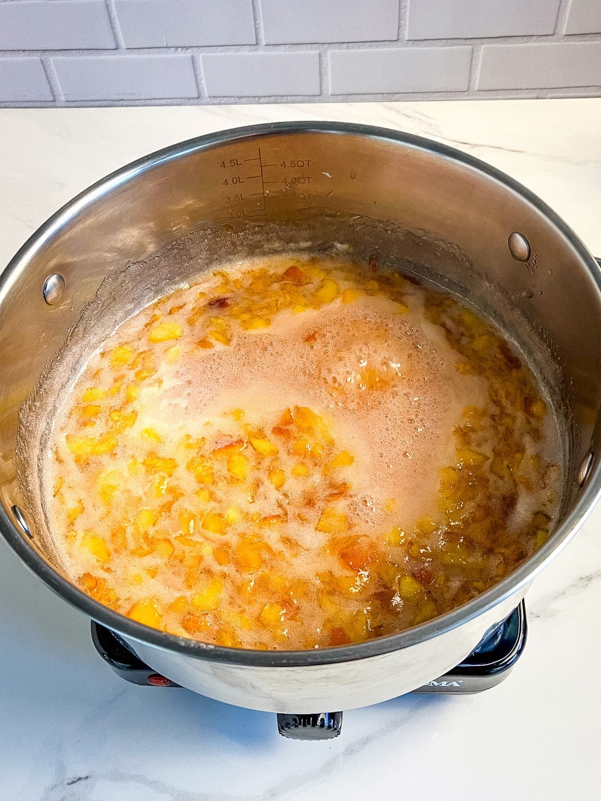 Peach jam is boiling in a pot.