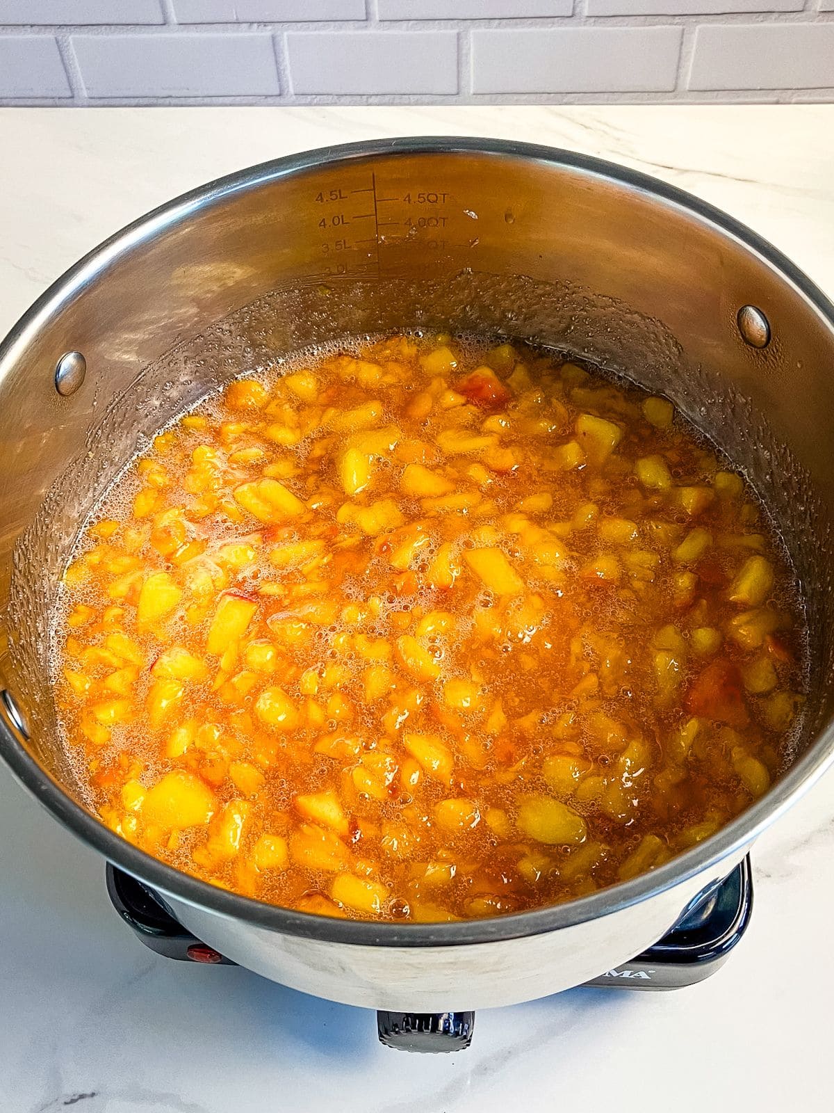 Diced peaches are cooking in a pot.