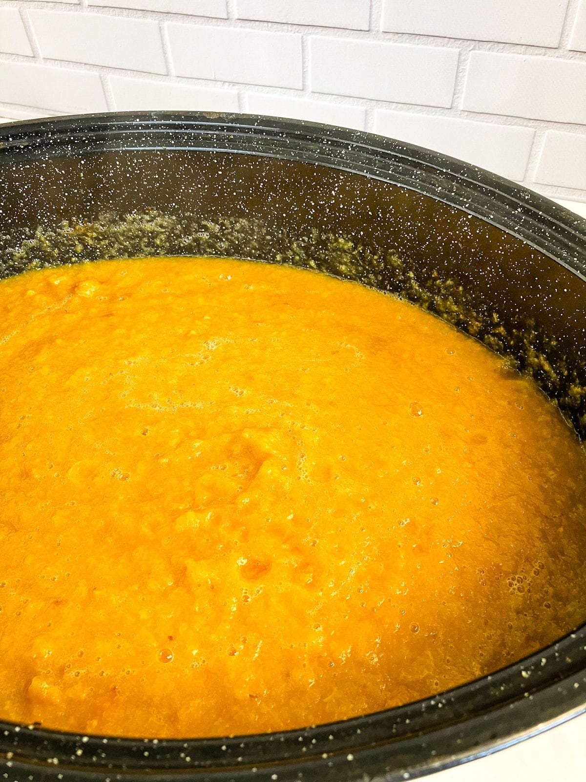 Pureed peaches in a black roasting pan.