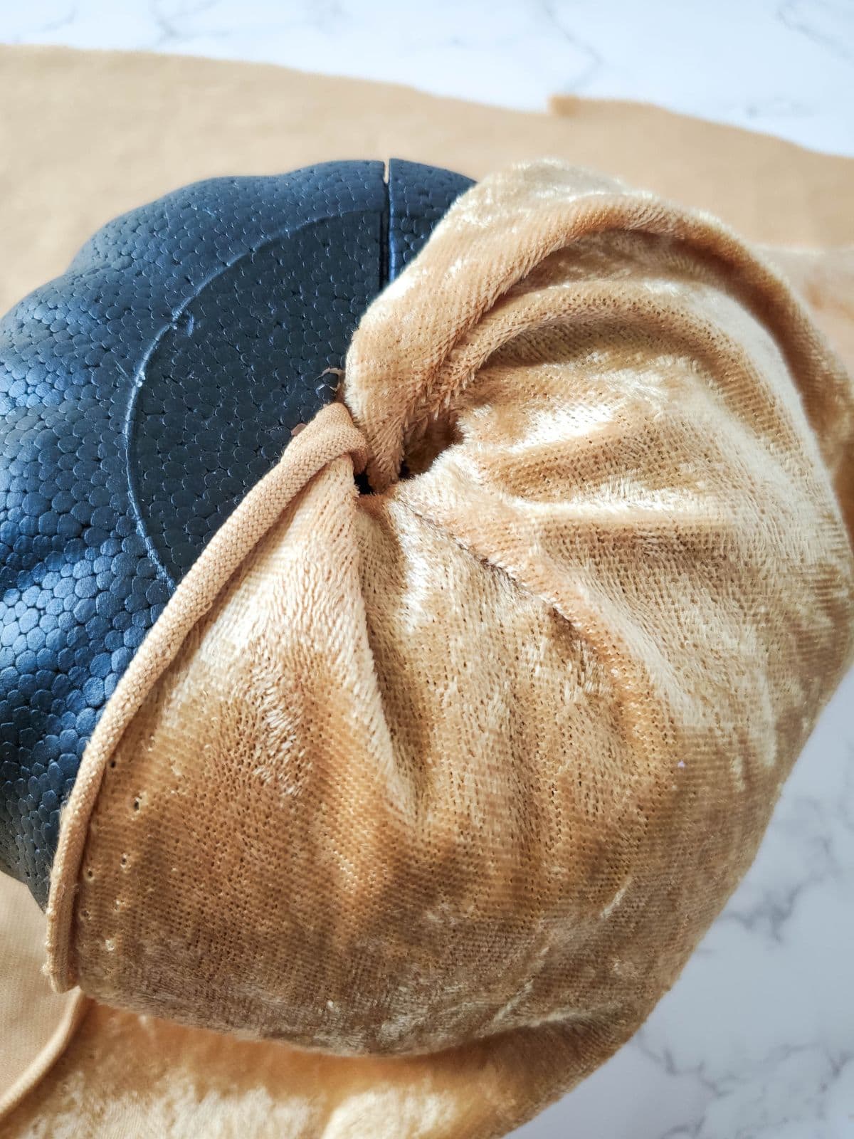 Wrapping the velvet cloth around the pumpkin and stuffing it into the hole.