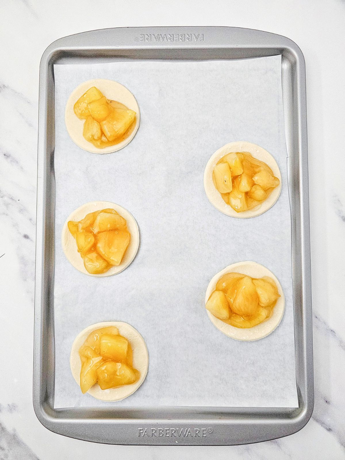 Adding the apple pie filling on top of the pie crust circles.