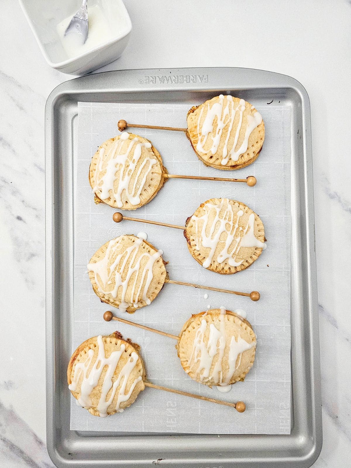 Adding the icing glaze to the apple pies.