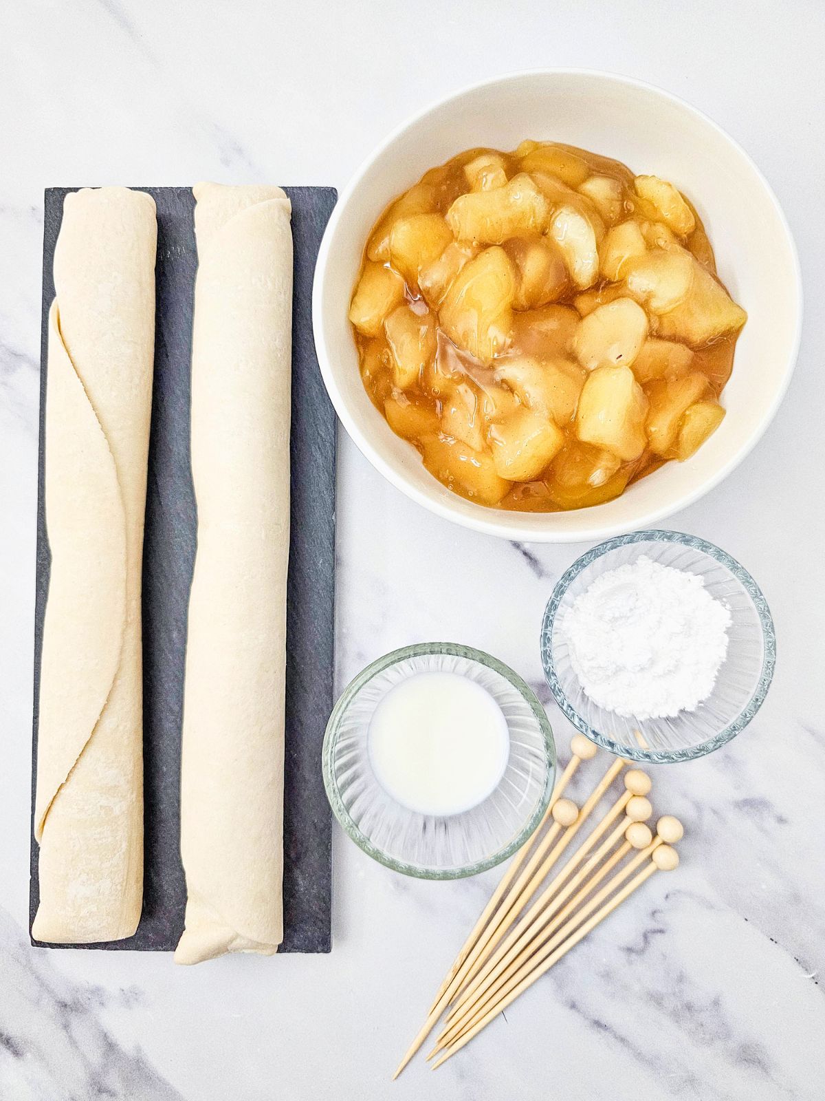 Two pie crusts, apple pie filling, powdered sugar, milk, and wooden skewers.
