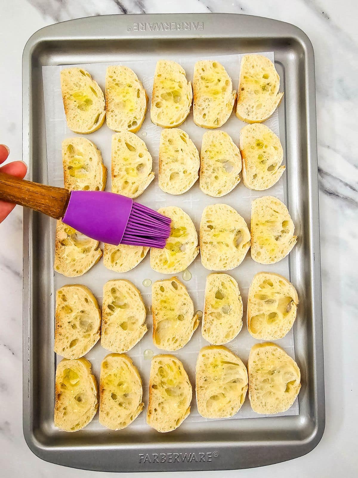 Basting the baguette slices with olive oil.