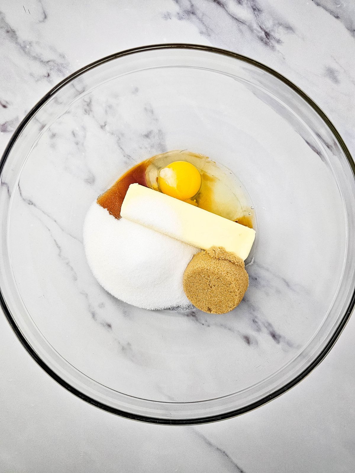 Brown sugar, white sugar, egg, butter, and vanilla in a mixing bowl.
