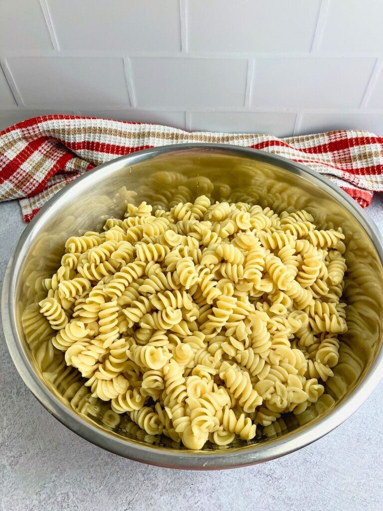 A large mixing bowl filled with cooked spiral pasta.