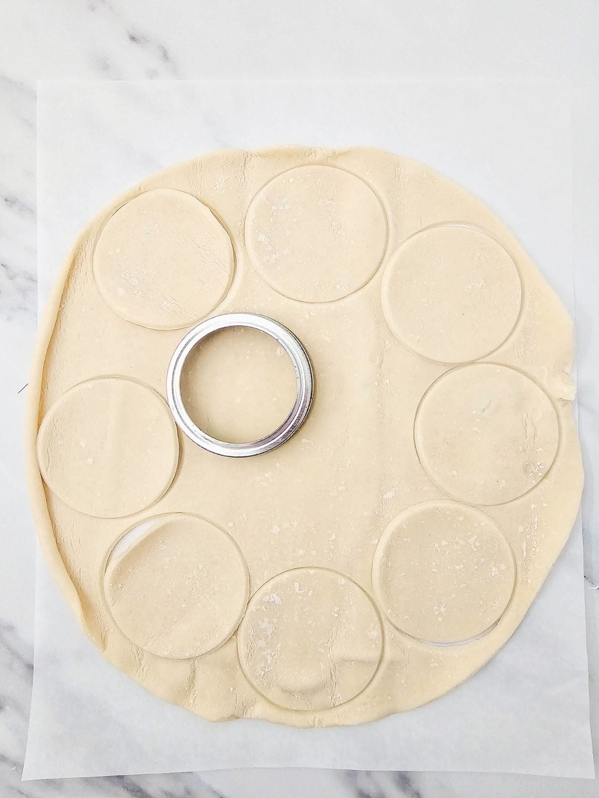 Cutting out pie crust circles with a mason jar lid.