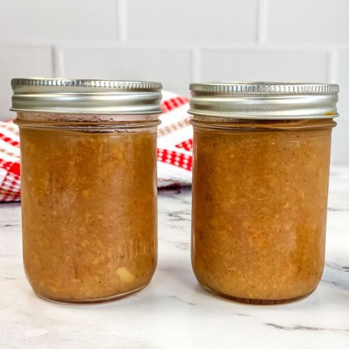 Two jars of homemade pear sauce on the counter.