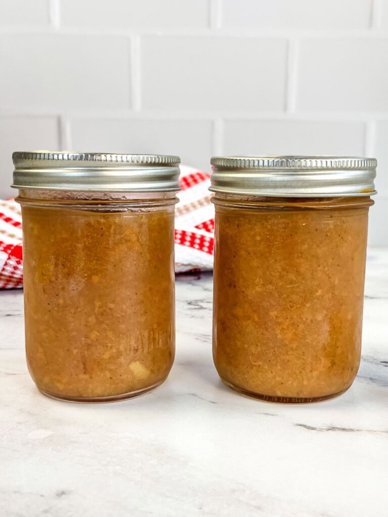 Two jars of homemade pear sauce on the counter.