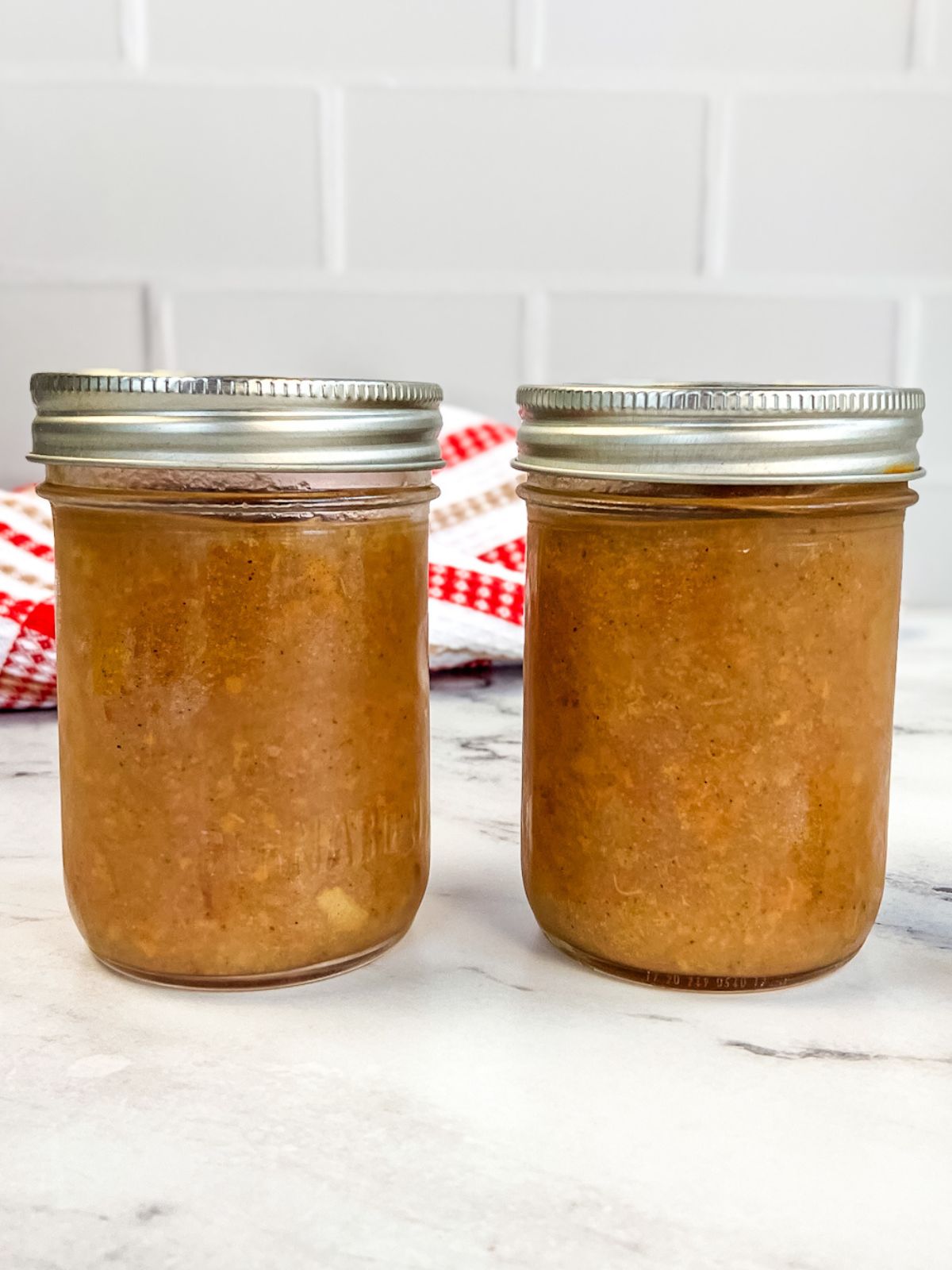 Two jars of homemade pear sauce on the counter.