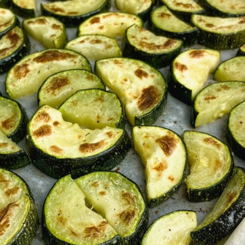 Sliced roasted zucchini on a sheet pan, baked and ready to eat.