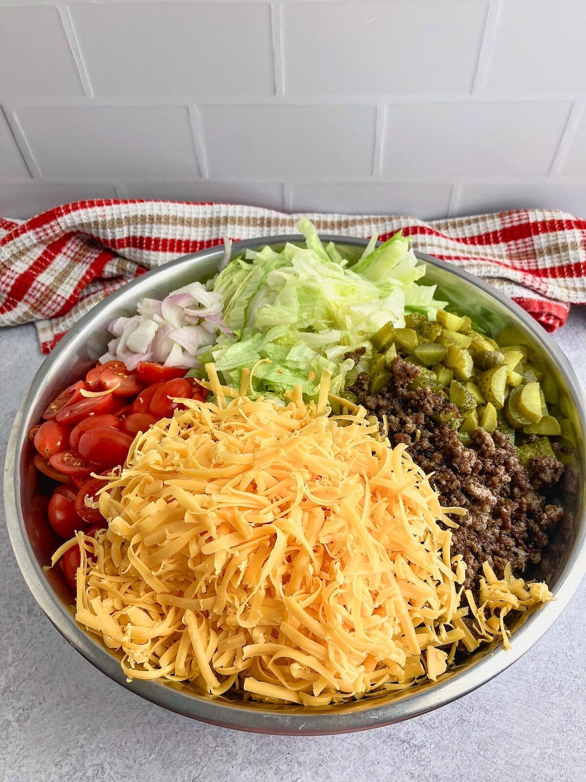 Ground beef, cheese, pickles, and vegetables added on top of the cooked pasta.