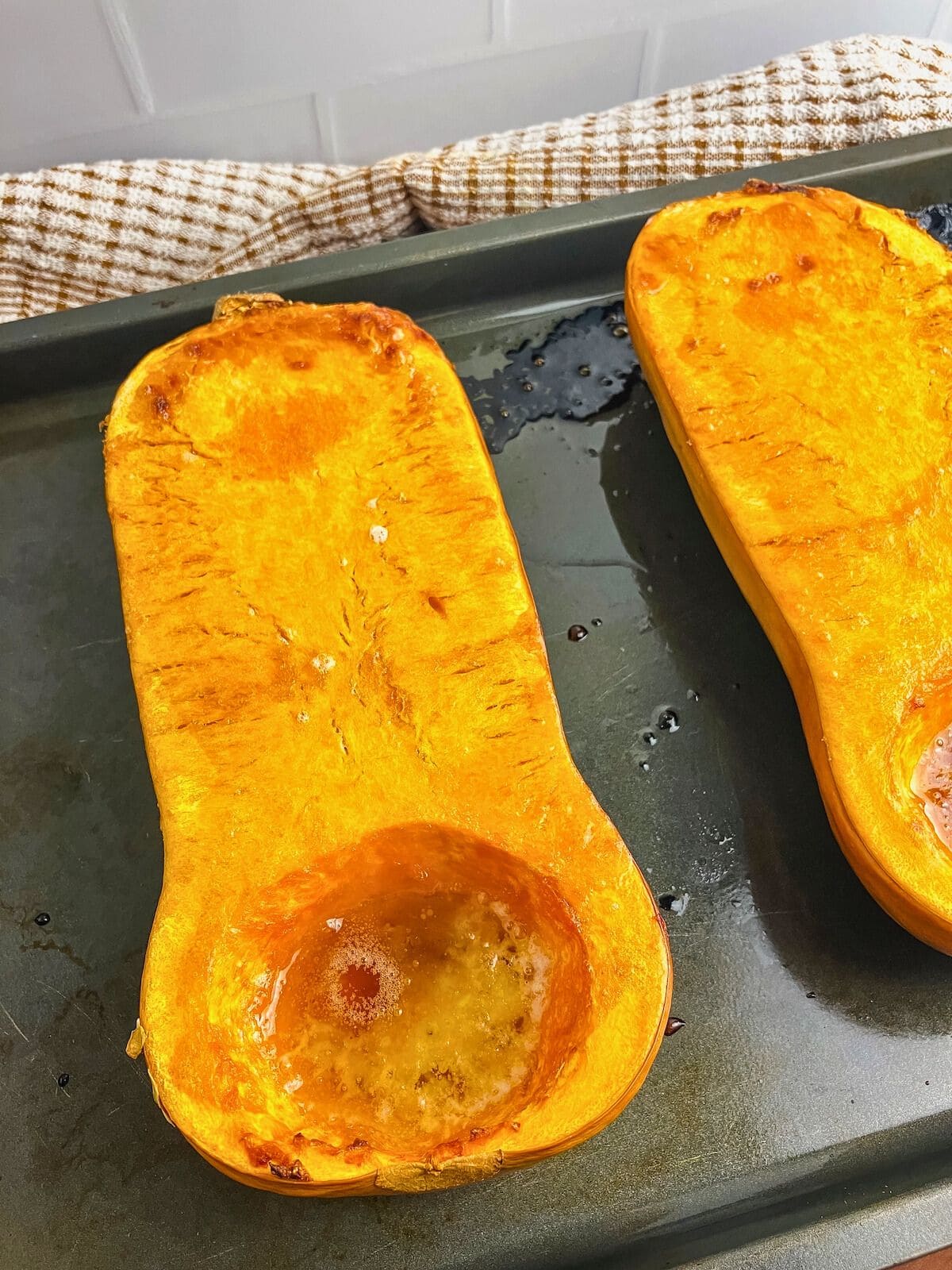 Whole roasted butternut squash with brown sugar on a baking sheet.