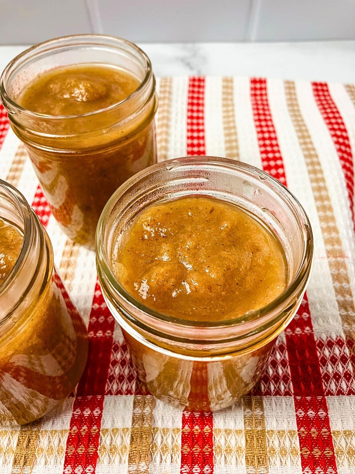 Pear sauce ladled into half-pint mason jars.