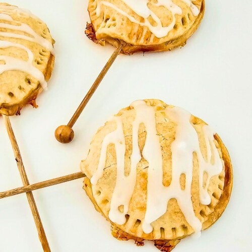 Mini apple pies on a stick on a serving tray.