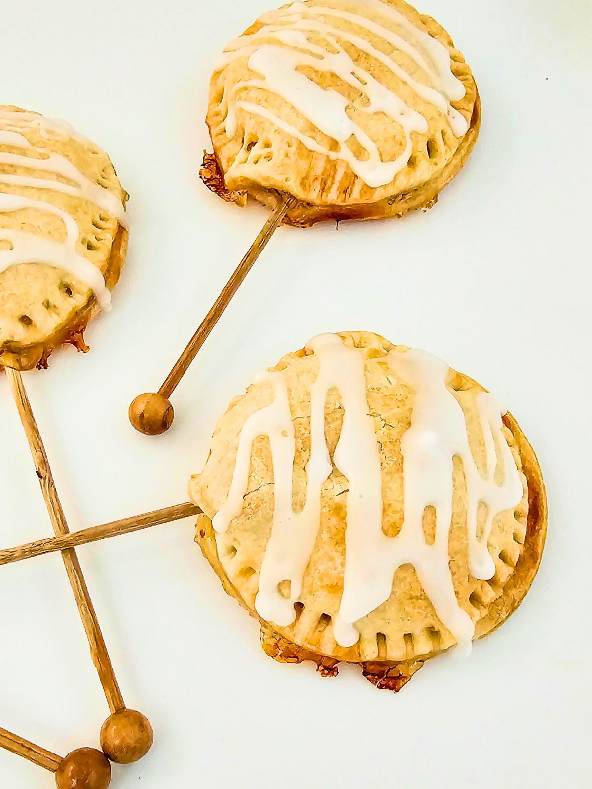Mini apple pies on a stick on a serving tray.