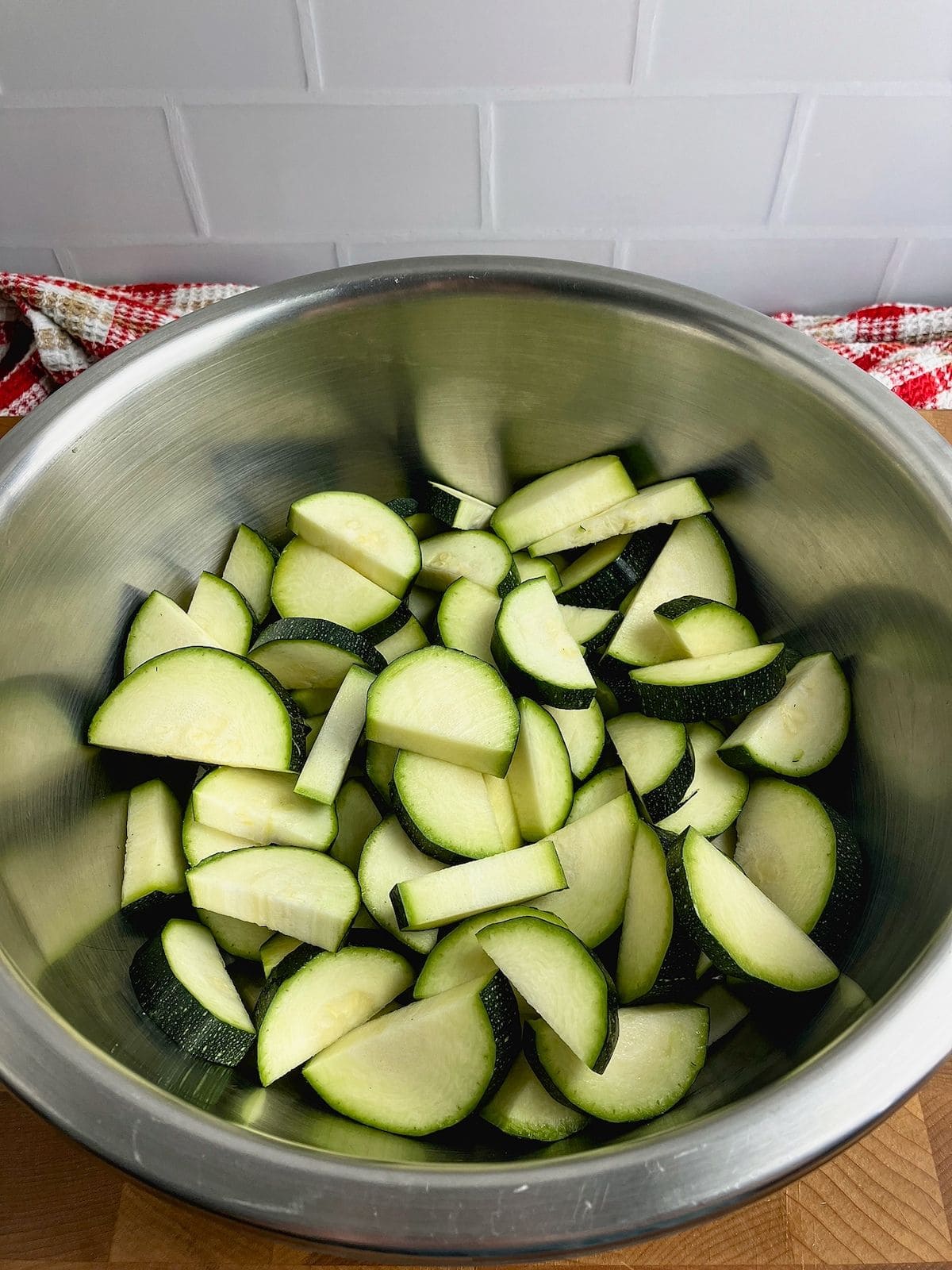 A large mixing bowl half filled with sliced zucchini.